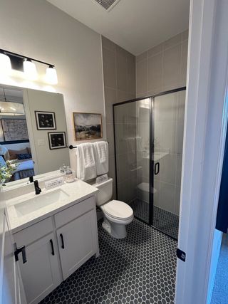 Model Home A modern bathroom with sleek glass shower, hexagon tile flooring, and stylish vanity with ample lighting.