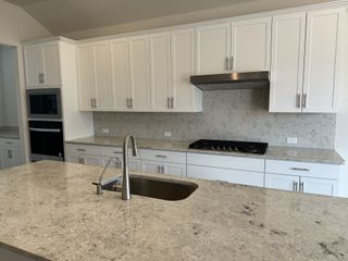 A modern kitchen with sleek white cabinets, a spacious granite countertop, and stainless steel appliances.