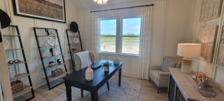 A chic home office with stylish shelves and large windows offering scenic views in Veranda by Brightland Homes.