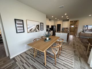 Model Home An inviting dining area with a wooden table and matching chairs, complemented by natural-toned decor. The open layout seamlessly connects to the kitchen and living area.