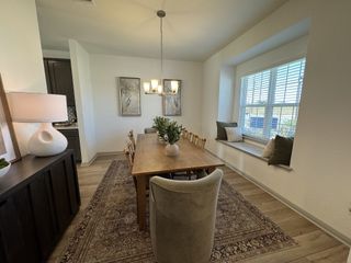 Model Home Bright dining area features a cozy window seat and elegant chandelier, perfect for intimate dinners and entertaining guests.