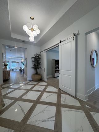 Modern hallway with marble-patterned tiles, elegant barn doors, chic lighting, and a touch of greenery.