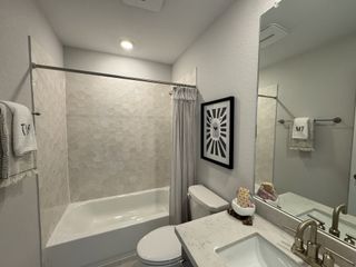 A modern bathroom with hexagonal tile accent, sleek white vanity, and stylish decor.