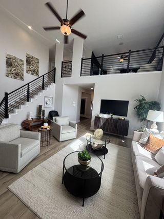 Model Home A bright, inviting living room with high ceilings, soft neutral furnishings, and a stylish modern railing leading upstairs.