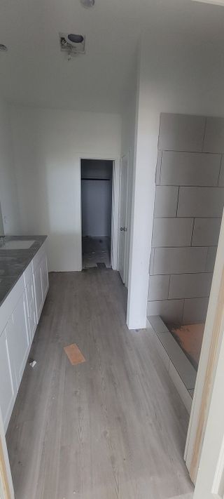 A partially finished bathroom with large tiled shower walls and a spacious walk-in closet.