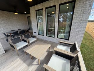 A chic patio with modern seating, large windows, and a stylish dining area, perfect for outdoor relaxation and entertainment.