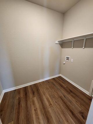 A functional laundry room with wood-look flooring, built-in shelving, and washer/dryer hookups.