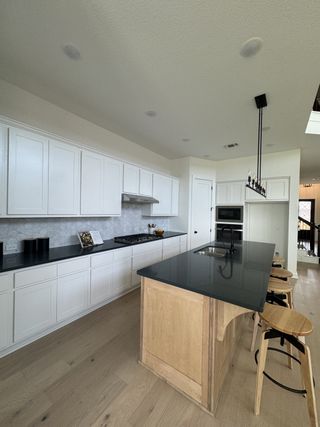 Model Home A contemporary kitchen featuring white cabinetry, a dark stone countertop, and a wood-accented island with stylish bar seating.