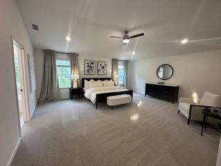 A spacious bedroom with elegant decor, featuring a king-sized bed, modern furniture, and ample natural light.