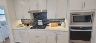 A close-up of a stylish kitchen with white cabinets, a hexagon tile backsplash, and stainless steel appliances, highlighting the details in a Davis Ranch home by Coventry Homes (San Antonio, TX)