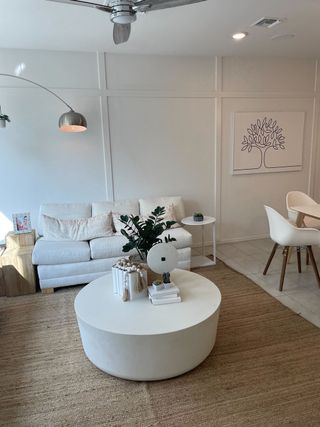 A cozy living room with a white sofa, modern art, round coffee table, and natural light.