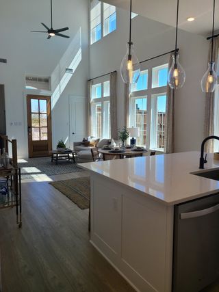 Model Home An elegant, open-concept living room with high ceilings, large windows, and sleek lighting fixtures.