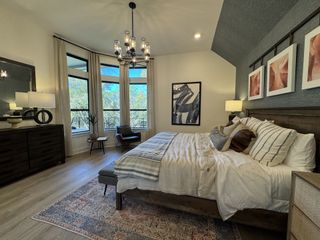 Model Home A cozy bedroom with modern lighting, large windows, and stylish decor in neutral tones.