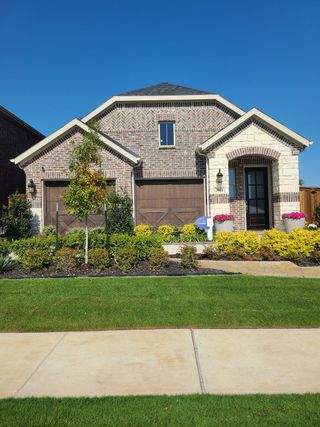 A charming brick home with lush landscaping in Spiritas Ranch by Mattamy Homes (Little Elm, TX).