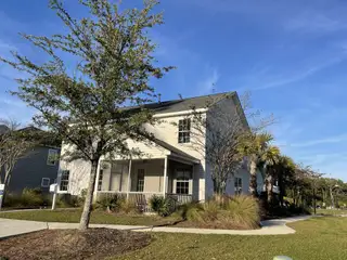 Street view A charming two-story home with a porch and manicured lawn in High Point at Foxbank by Dream Finders Homes (Moncks Corner, SC).