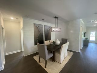 A cozy dining area featuring a sleek dark wood table, elegant chairs, and modern pendant lighting set against shiplap walls.