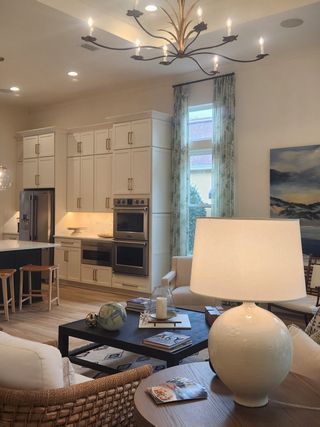 A stylish open kitchen with white cabinetry, sleek appliances, and a statement chandelier for a warm and elegant atmosphere.