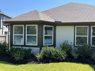 Charming white siding home with lush landscaping in Massey Oaks - Estate Series by Meritage Homes (Pearland, TX).