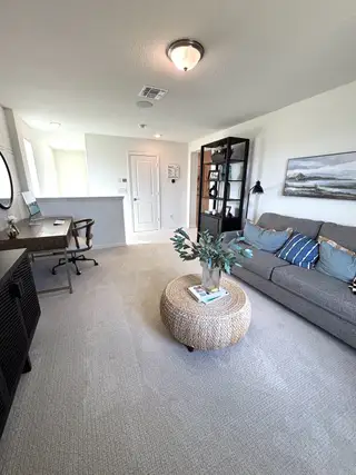 A cozy living area featuring a stylish desk, comfortable gray sofa, and decorative basket coffee table for a modern touch.