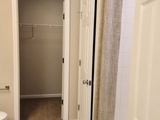 A contemporary bathroom with a spacious walk-in closet, neutral tones, and a shower-tub combination for convenience.