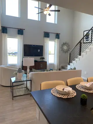 Model Home A bright living area with high ceilings, modern decor, and natural light pouring in through tall windows.