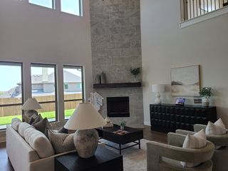 A contemporary living area with tall windows, a stone fireplace, and elegant furnishings, exuding warmth and style.