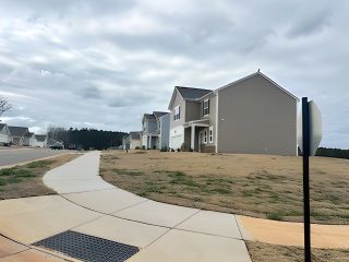 Modern gray homes with spacious yards line a peaceful street in Bryson's Ridge by Starlight Homes (Spring Hope, NC).