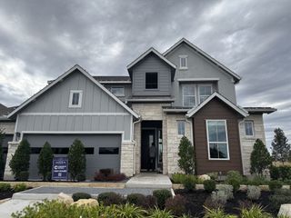 A beautiful stone and siding home with a lush garden in Santa Rita Ranch by Chesmar Homes (Liberty Hill, TX).