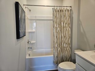 Model Home A modern bathroom with a sleek tub, patterned shower curtain, and minimalist decor.