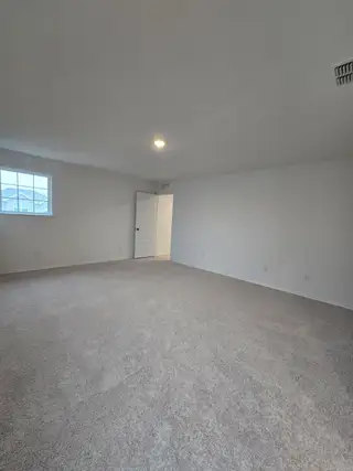 A spacious, freshly carpeted room with neutral walls, ready for your personal touch and design vision.