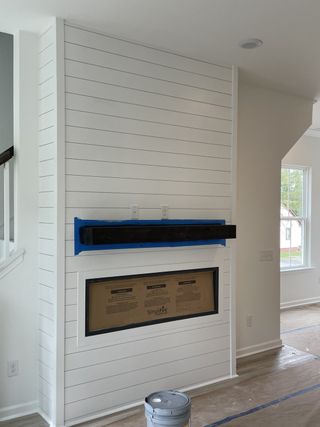 A sleek living room fireplace with white shiplap paneling, dark mantel, and modern design elements.