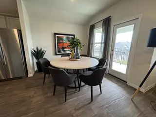 A stylish dining space with a round wooden table, modern black chairs, and large windows for natural light.