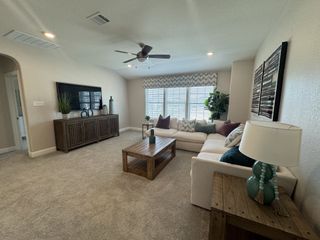 A cozy living room with plush carpeting, a large sectional sofa, an table, and a decorative TV console, creating a comfortable gathering space.