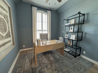 A cozy home office with a wooden desk, modern shelves, and elegant decor against soft blue walls and an arched window.
