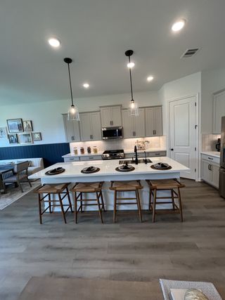 Model Home A modern kitchen with a spacious island, pendant lighting, and sleek cabinetry, perfect for cooking and entertaining.