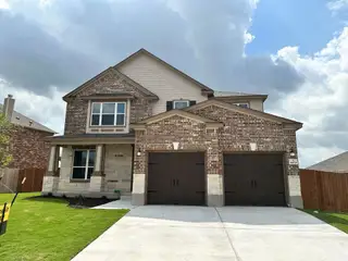 A two-story brick and stone home, numbered 4673, in Salerno by KB Home (Round Rock, TX) features a double garage and a neatly landscaped front yard.