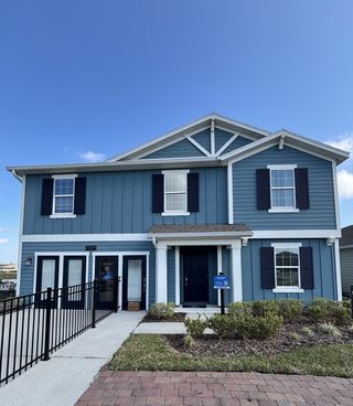 Street view A charming blue siding home with dark shutters and a landscaped path in Storey Creek: Manor Collection by Lennar (Kissimmee, FL).