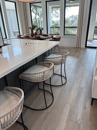 Model Home A modern kitchen with a large quartz island, black pendant lighting, and white cabinetry in Esperanza by Perry Homes (Boerne, TX).