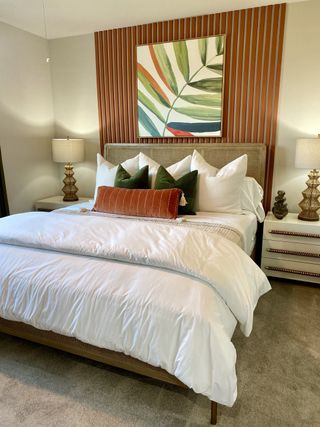 Model Home A cozy bedroom with a plush bed, accent wall, abstract art, and stylish lamps.