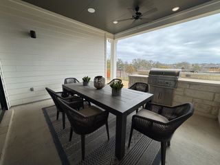 A cozy covered patio with a sleek dining set, stylish chairs, and a built-in grill, perfect for outdoor entertaining.