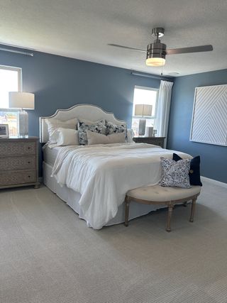 A serene bedroom featuring a plush bed, elegant nightstands, and soft blue walls with natural light filtering in.