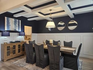 A stylish dining room with coffered ceilings, navy accent walls, and modern lighting in Kingston by DRB Homes (Locust Grove, GA).
