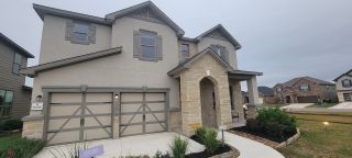 A beautiful modern home with stone and stucco finish, showcasing a spacious front yard in Preserve at Culebra by KB Home (San Antonio, TX).