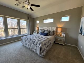 A cozy bedroom with a tufted headboard, ample natural light, and neutral tones for a serene atmosphere.