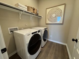 Model Home A modern laundry room featuring stacked appliances, open shelving, and stylish decor.