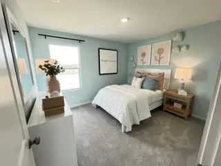 Model Home A cozy bedroom with light blue walls, floral decor, and plush bedding, creating a serene and inviting atmosphere.