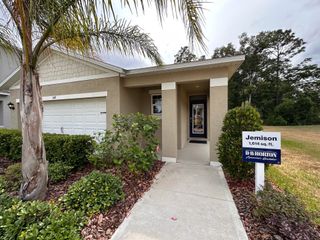 A charming beige home with a sleek entry and lush landscaping in Pelham Park by D.R. Horton (Deland, FL).