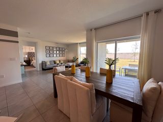 A bright and inviting dining area with a large wooden table, plush seating, and sliding doors leading to the backyard.