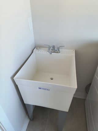 A sleek utility sink with a modern faucet set in a minimalist space, perfect for laundry or cleaning needs.