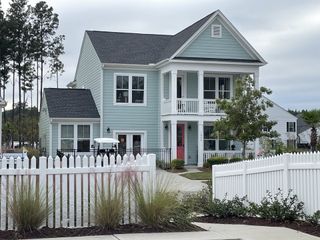 A charming blue home with a spacious porch and white picket fence in Homecoming by True Homes (Ravenel, SC).